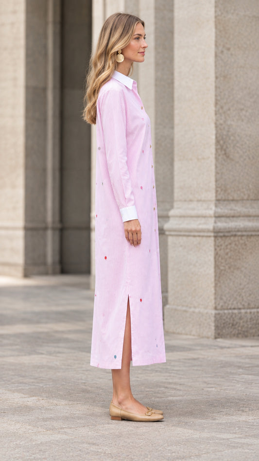 Side profile of woman wearing pink striped embroidered maxi shirt dress showing side slit