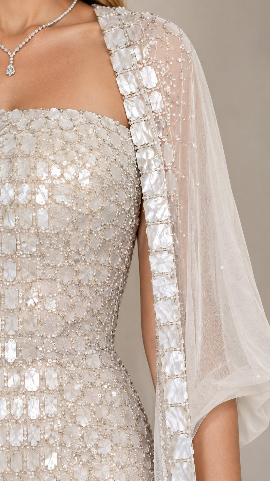 Close-up detail of jeweled trim and sequin embellishments on champagne gown and cape