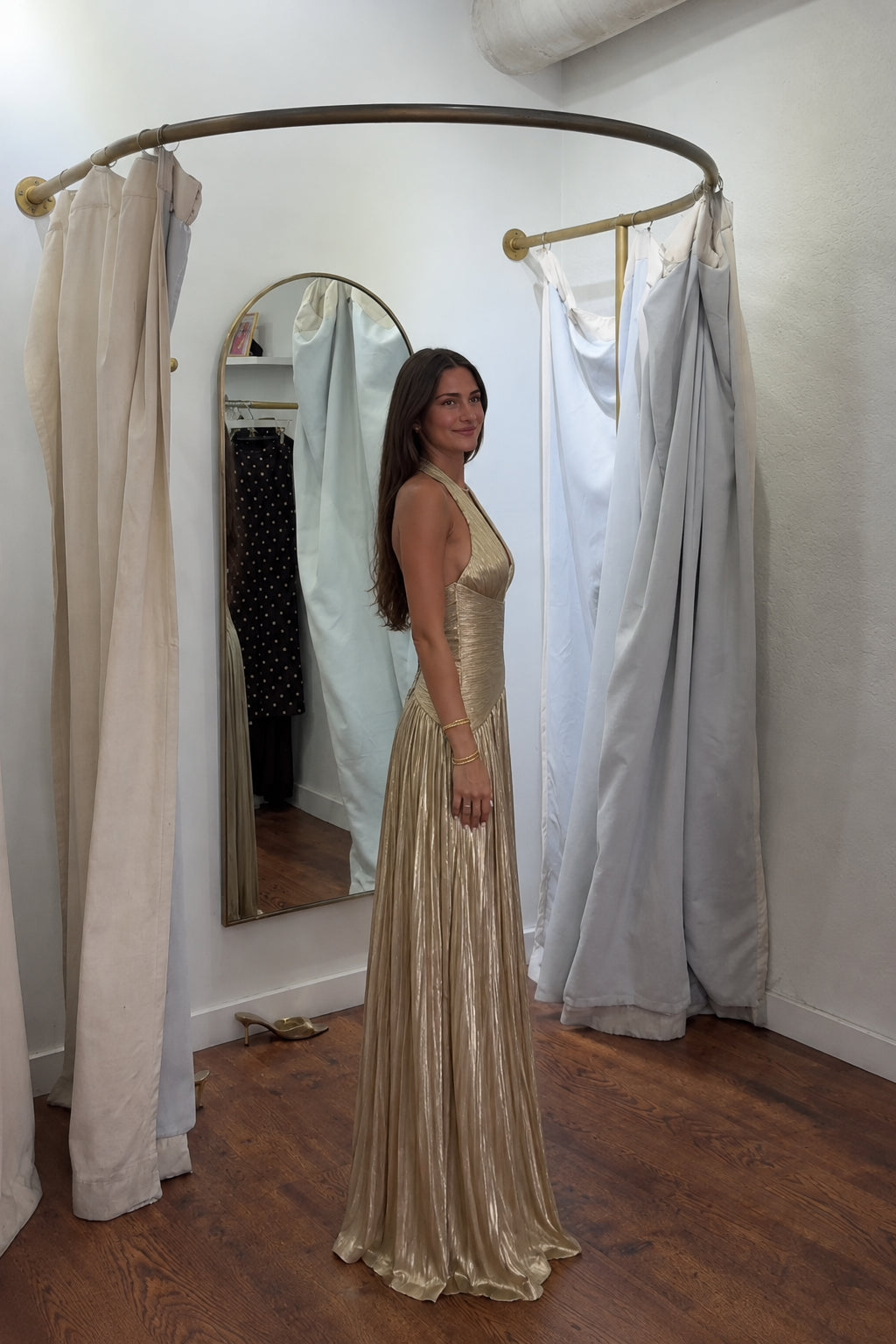 Side profile view of gold metallic pleated halter evening gown