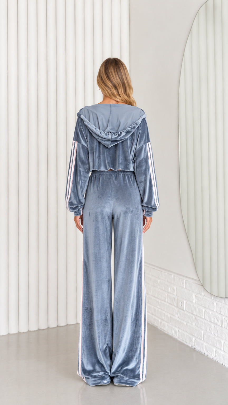 Back view of woman wearing dusty blue velour cropped hoodie and wide leg track pants