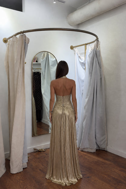 Back view of gold metallic pleated maxi dress showing open back and lace-up closure
