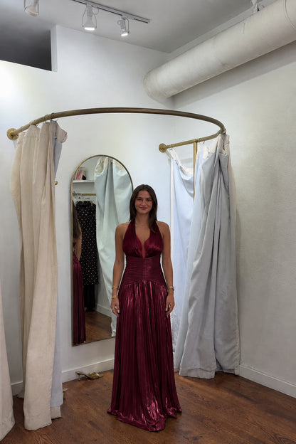 Front view of model wearing burgundy wine red metallic pleated halter evening gown
